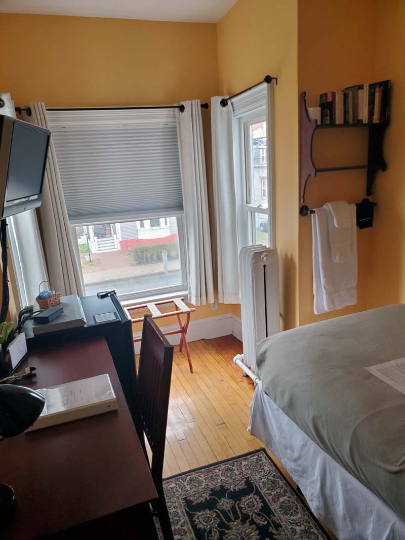 twin bed, nook with 3 windows, wall shelf, cast-iron radiator, desk