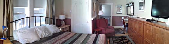 panoramic view of room with king bed, 2 Murphy beds in up-position, double-window, reclining chair