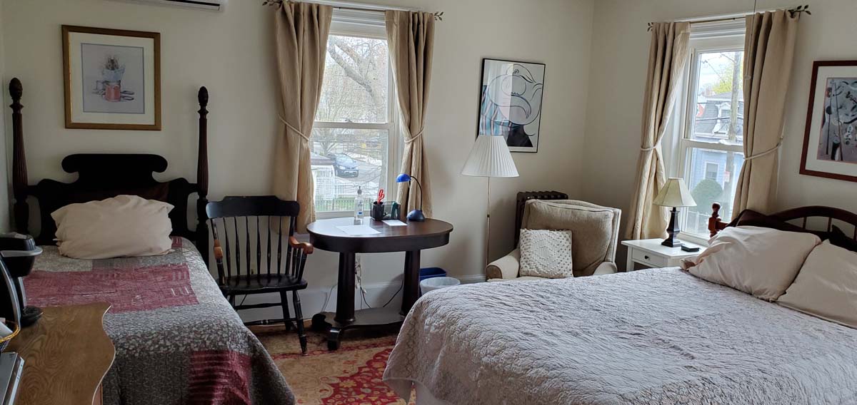 wide angle view of room with both queen and twin beds, 2 windows, desk and comfy chair