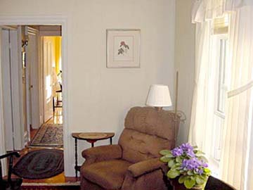 corner of sitting room: comfy chair, window, African violet